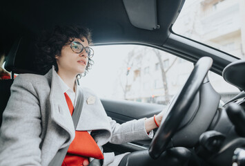 Smartly dressed female entrepreneur driving a car, showcasing independence and business lifestyle.