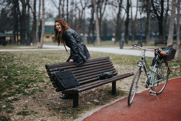 Stylish young businesswoman with a bike takes a leisurely pause on a park bench, exuding confidence and happiness.