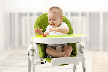 Children toys. Cute little boy playing with spinning tops in high chair at home