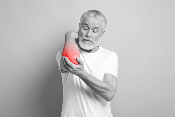 Arthritis symptoms. Man suffering from pain in his elbow on grey background. Black and white effect...