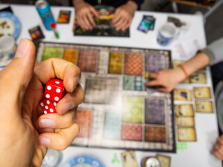 Hand with red dice on game board with one four and five and cards - 771874924