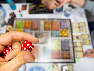 Hand with red dice on the game board with a four - 771874946