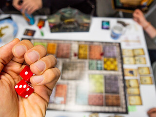 Hand with red dice on the game board with a one and a three - 771874994