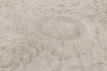 Fototapeta na wymiar Children's entertainment sand white castle with seashells on the beach