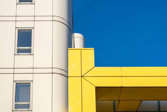 Modern, yellow, white building against clear blue sky.