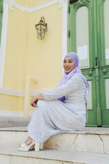 Portrait of young Asian woman wearing hijab sitting and posing a staircase at Mosque.