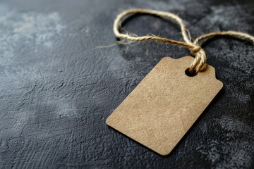 Close-up shot of a brown tag with a rope lying on a black surface, showcasing an empty price tag with space around it for text or design