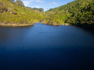 Calm lake water and bush covered hillside landscape