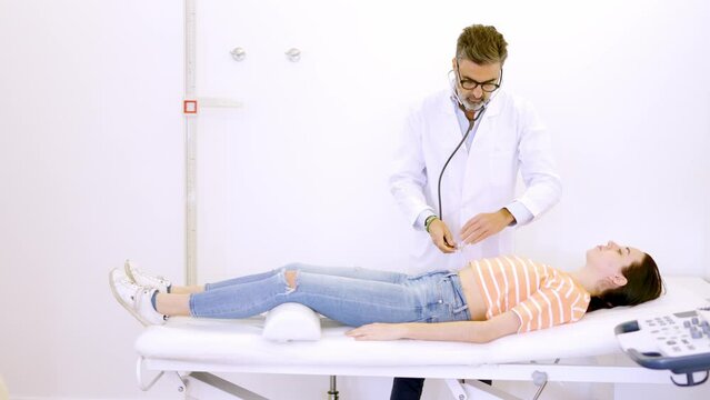 Doctor auscultating the patient's abdomen with a stethoscope