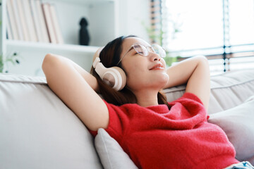 Relaxed young Asian woman enjoying rest on comfortable sofa, calm attractive girl relaxing on...
