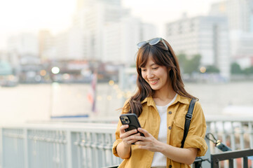 Fototapeta premium young Asian woman in 30s on a solo adventure. Technology in hand, she captures the essence of cultural exploration and joyful discovery.