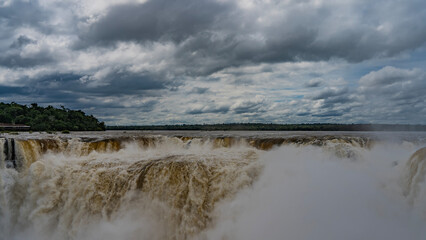 The incredible waterfall - Devil's Throat. Powerful streams of water collapse into the abyss from the ledge of the riverbed. White foam. A cloud of spray in the air. Iguazu Falls. Argentina