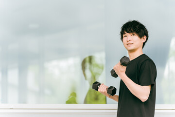 ダンベルで腕と肩の筋肉を鍛える若いアジア人男性
