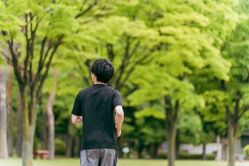 公園でウォーキング・ジョギング・ランニング・運動・有酸素運動・トレーニングをする若い男性
