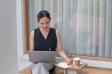 Businesswoman Planning with Laptop and Notebook