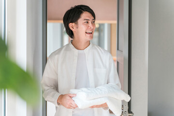 洗濯物のバスタオルを運ぶ男性・家事をする男性  © buritora