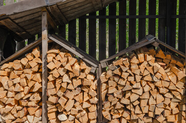 Firewood is prepared for the cold and stacked under a canopy