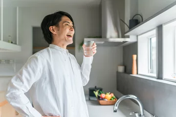 Foto op Plexiglas キッチンで水・白湯を飲む若いアジア人男性（水分補給・温活）  © buritora