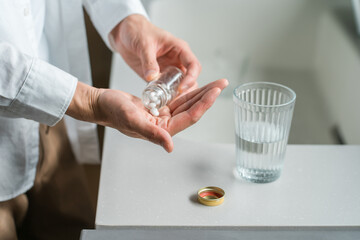 キッチンで内服薬・サプリ・医薬品を飲む病気の男性の手元
