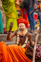 Portrait of an old sadhu baba with ash on his face sitting on ghats and blessings devotees.	