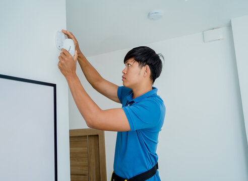 A technician installing motion sensor detector in a modern apartment.