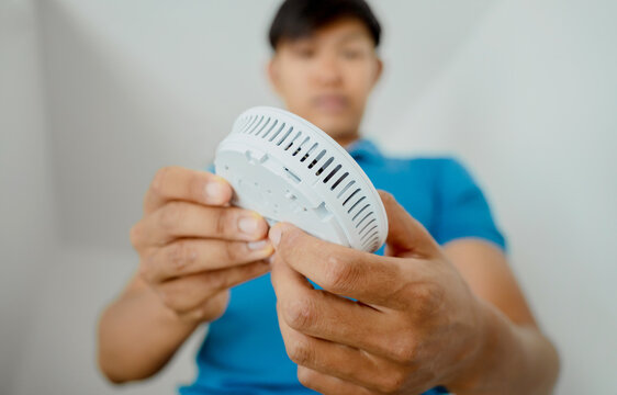 Technician installing fire safety detector in a modern apartment