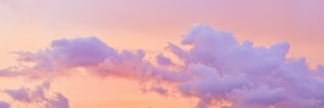 Aesthetic Pastel Sunset, violet fluffy clouds on pink peach colored sky, dreamy cloudscape pastel tones, surreal dreamscape at sunset, soft colorful heaven, wide banner, panoramic view.