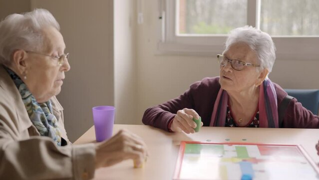 Women having fun playing Parcheesi board game in a geriatric