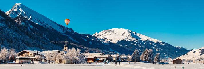 High resolution stitched alpine winter wonderland panorama with a hot air balloon near Tannheim,...