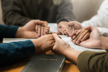 Group of young Christians praying, holding hands and praying together The concept of praying to God in the home as a team Pray to God with the Bible for forgiveness and faith.