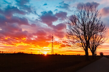 Sunset with a dramatic sky and overland high voltage lines near Tabertshausen, Deggendorf, Bavaria, Germany - obrazy, fototapety, plakaty