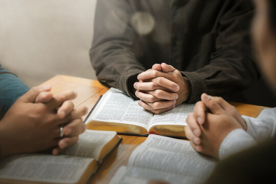Ideas for praying to God in the home as a team Young men sitting and praying together Ready to pray to God with the Bible asking for forgiveness and faith.