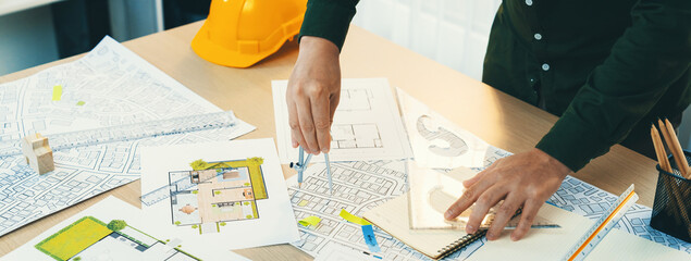 A portrait of architect using divider to measure blueprint. Architect designing house construction...