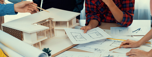 Architect team analysis and brainstorming about house construction at meeting table with house...