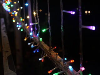 A close-up photo of colorful twinkling lights hanging at night gives off a festive feel
