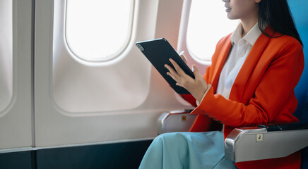 Asian executive excels in first class, multitasking with digital tablet, and smartphone. Travel in...