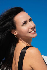 Beautiful brunette girl smiling on a background of blue sky. the wind blows long hair. merging with...
