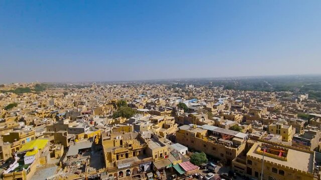 Panning aerial drone shot from golden fort showing the city cityscape of Jaisalmer city in thar desert a famous tourist landmark made of gold sand stone buildings and havelies