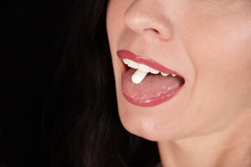 White oval tablet, capsule on the tongue of a girl, woman, close-up. Placebo concept. - obrazy, fototapety, plakaty