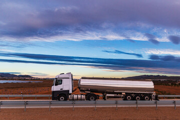 Tanker truck for transporting food liquids circulating at dawn, side view.