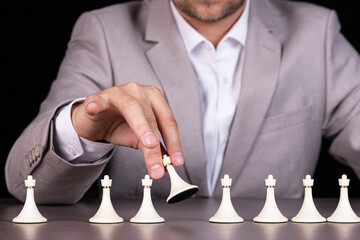 Man, businessman holds a white pawn. White pawns are in a row.