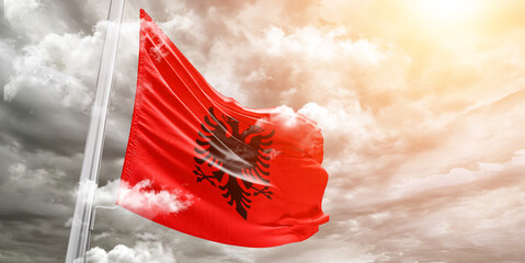 Albania national flag cloth fabric waving on beautiful cloudy Background. - obrazy, fototapety, plakaty
