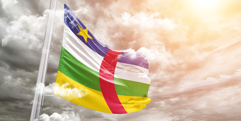 Central African Republic national flag cloth fabric waving on beautiful cloudy Background.