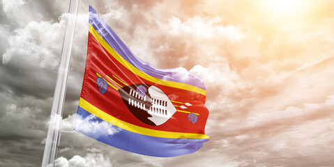 Eswatini national flag cloth fabric waving on beautiful cloudy Background.