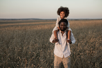 happy african dad and daughter on a summer walk in a field	