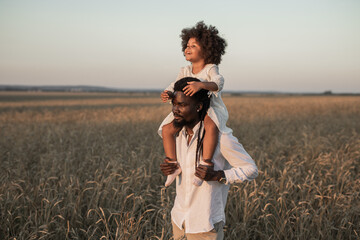 happy african dad and daughter on a summer walk in a field	