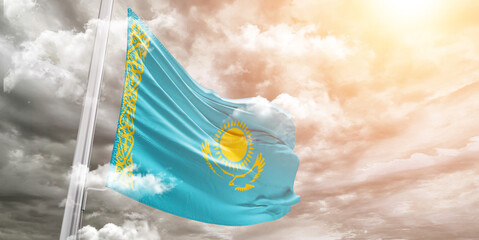 Kazakhstan national flag cloth fabric waving on beautiful cloudy Background.
