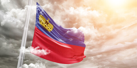 Liechtenstein national flag cloth fabric waving on beautiful cloudy Background.