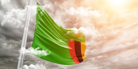 Zambia national flag cloth fabric waving on beautiful cloudy Background.