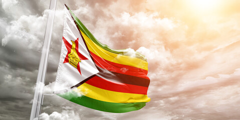 Zimbabwe national flag cloth fabric waving on beautiful cloudy Background.